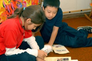 Two children reading together on the floor.